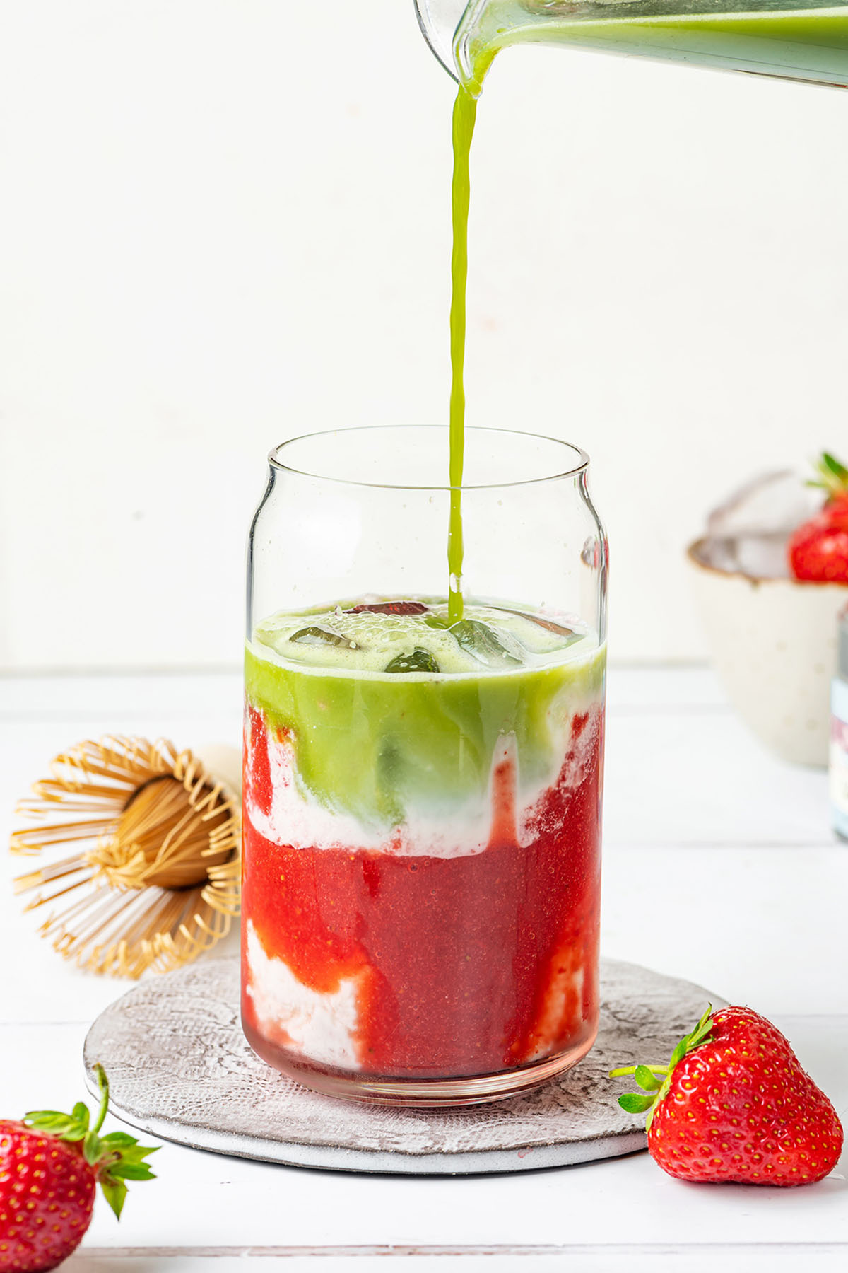Pouring the matcha into a glass with strawberry puree and milk
