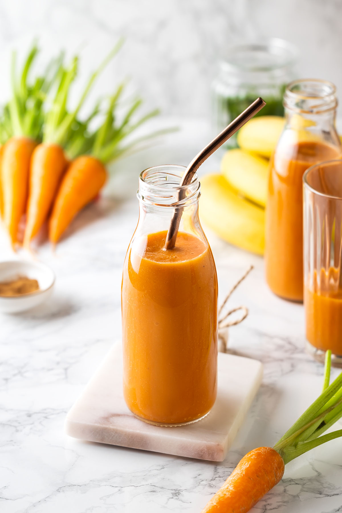 Carrot and Banana Smoothie in a glass bottle with a straw inside