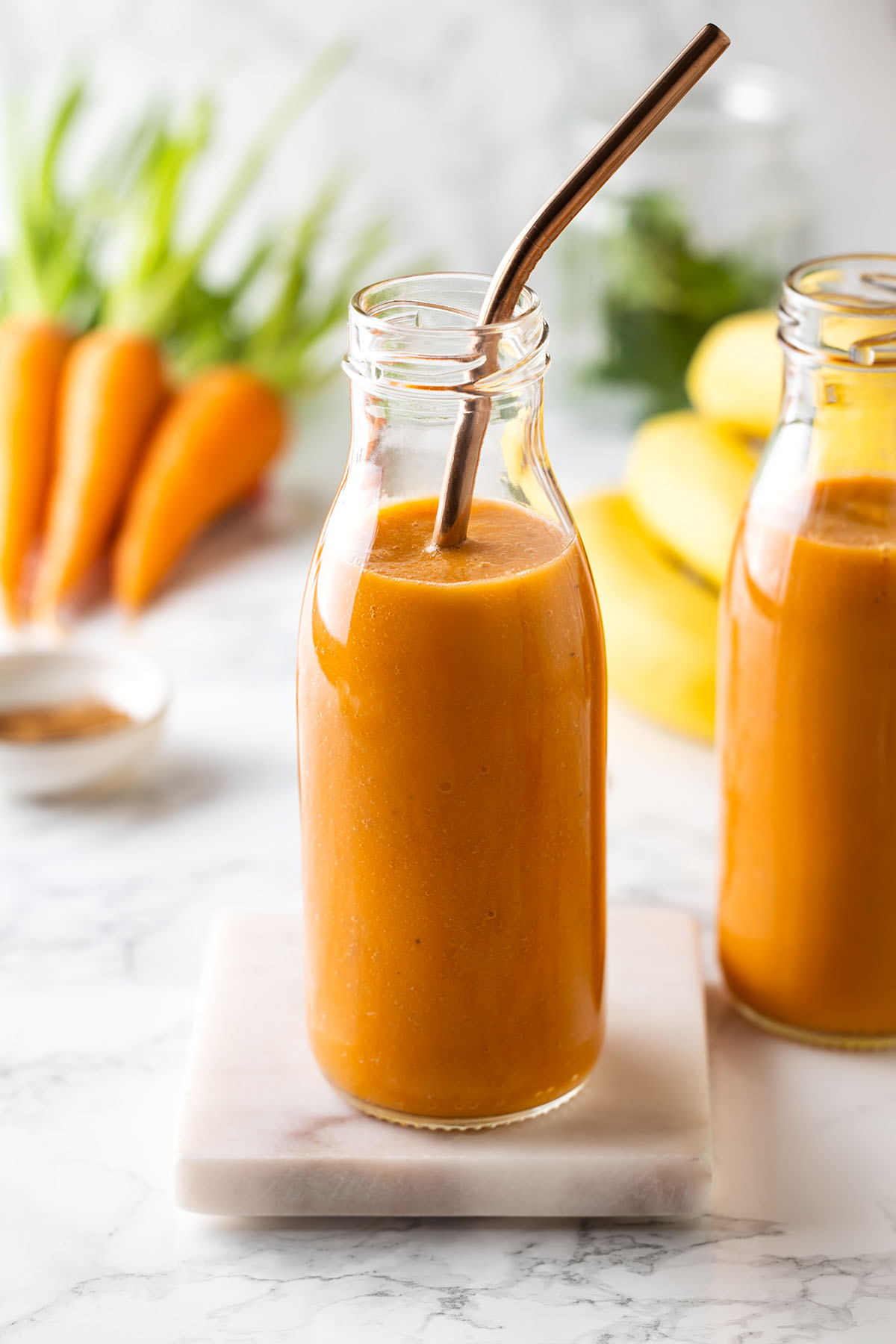 Bottle with carrot banana smoothie with a straw