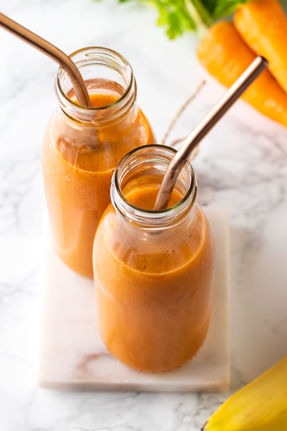 Carrot smoothies in two bottles with straws