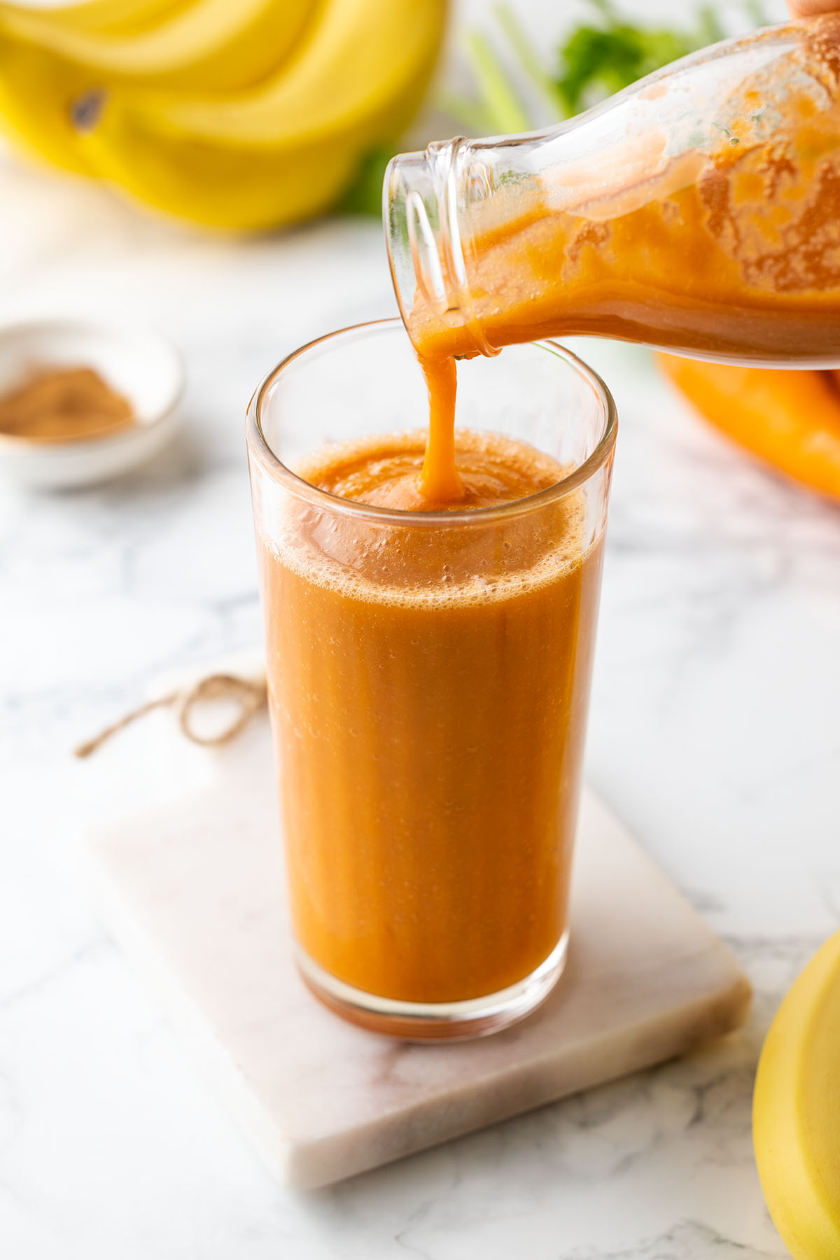 Pouring carrot smoothie in a glass