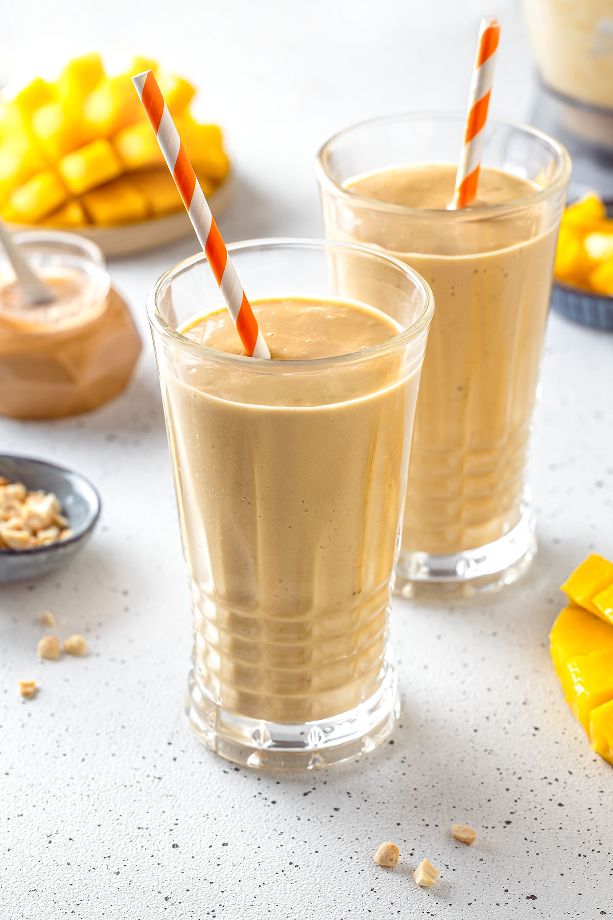 Two glasses with mango peanut butter smoothie