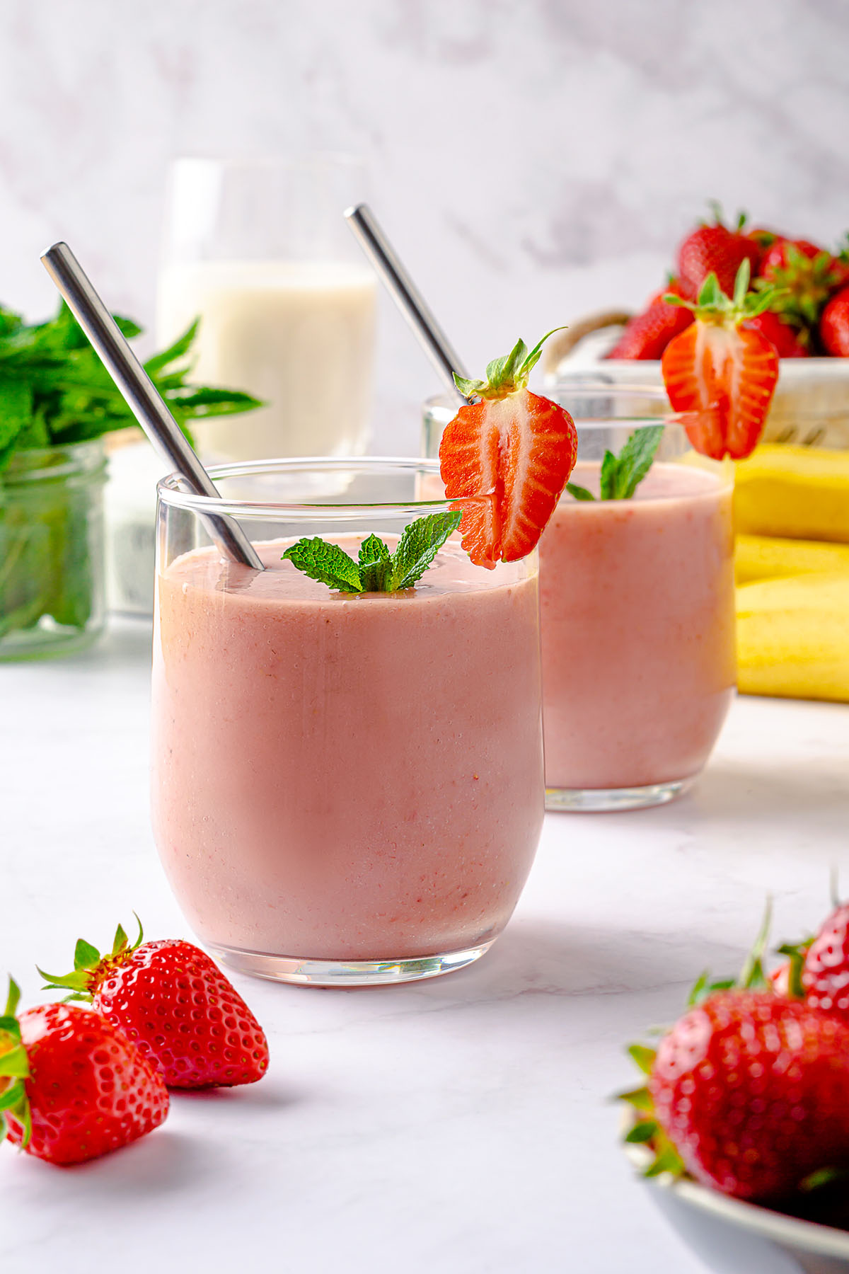 Strawberry banana avocado smoothie in a glass decorated with fresh strawberry