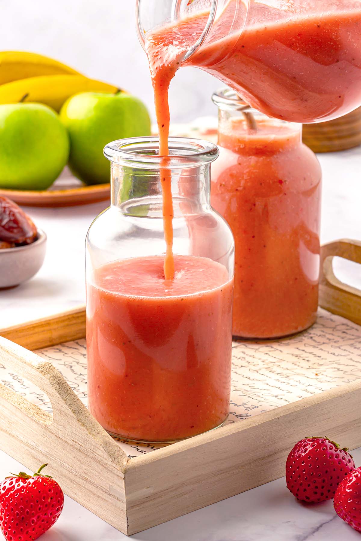 Pouring strawberry apple smoothie into a bottle