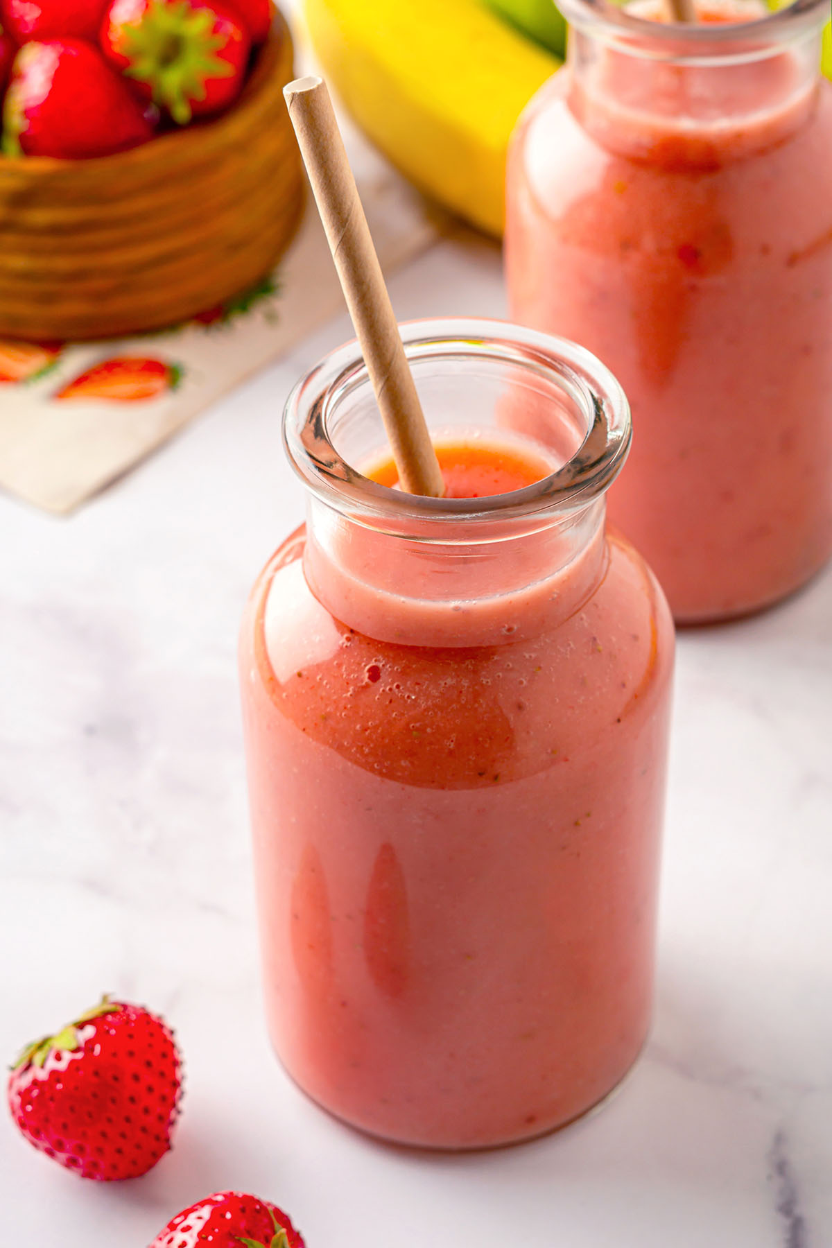 Bottles of strawberry apple smoothie with straw inside