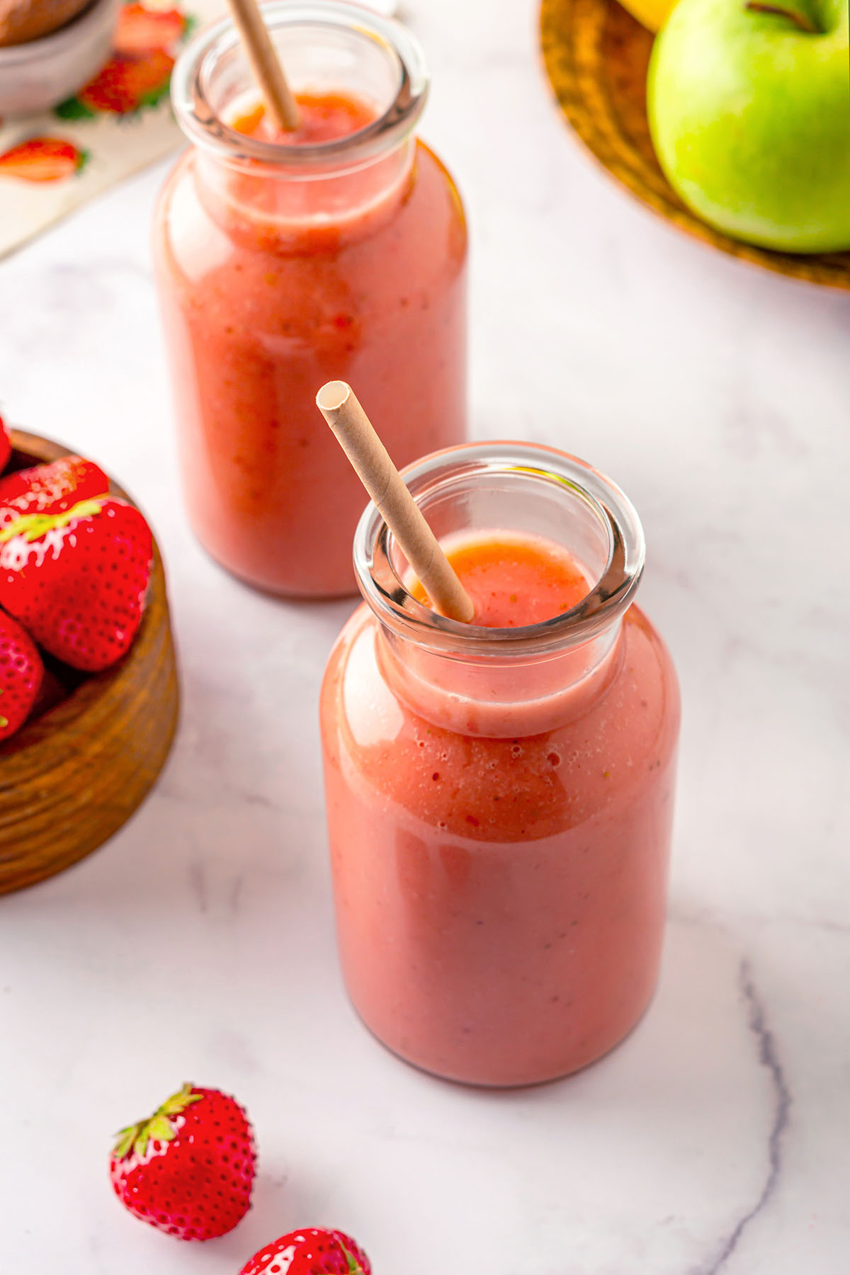 Bottles of strawberry apple smoothie with straws inside