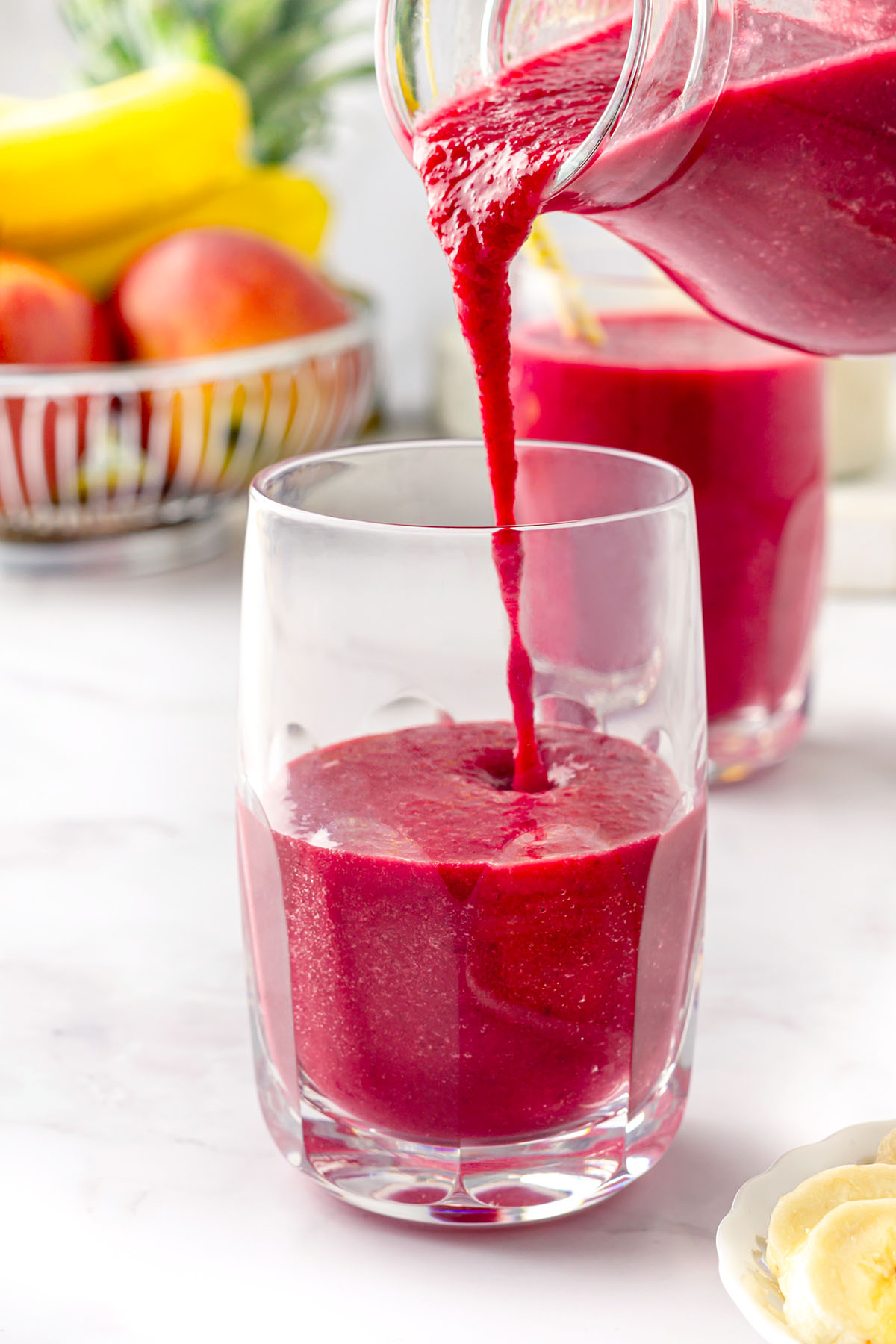 Pouring beet pineapple smoothie in a glass