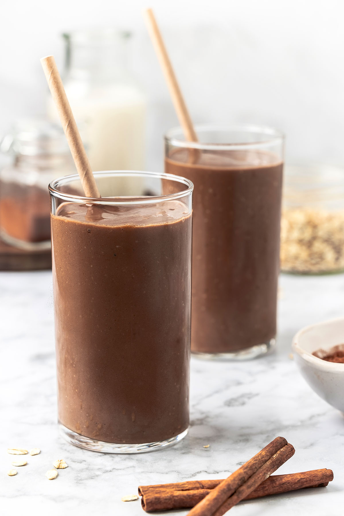 Two glasses with chocolate smoothie with straws inside