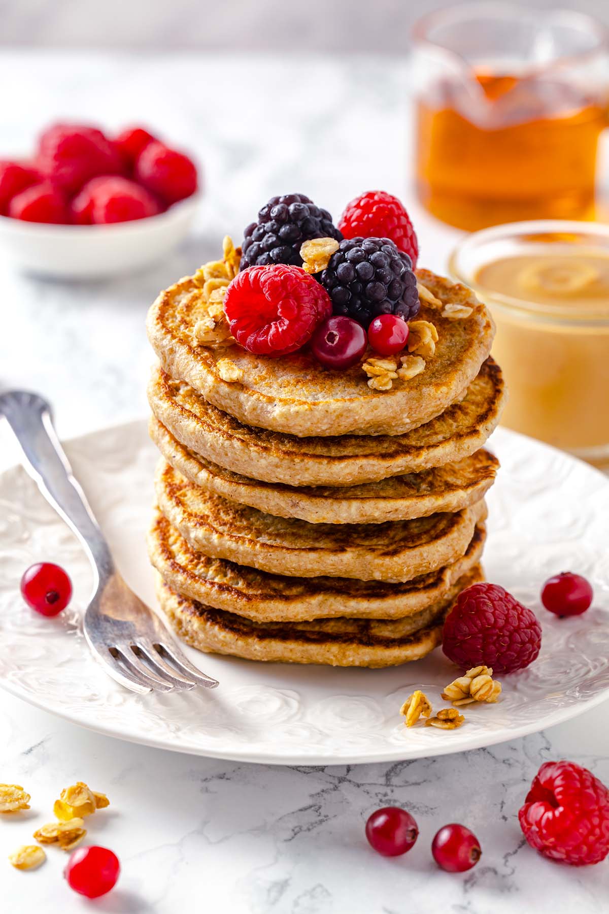 Stack of peanut butter oatmeal pancakes decorated with berries and granola