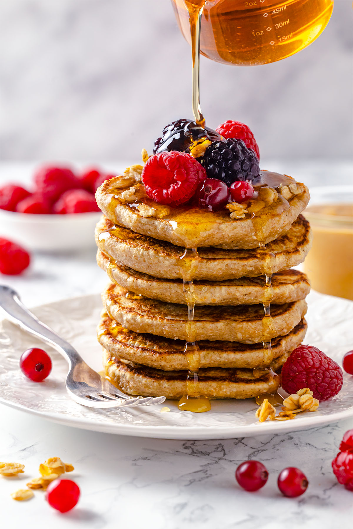 Pouring maple syrup over oatmeal pancakes