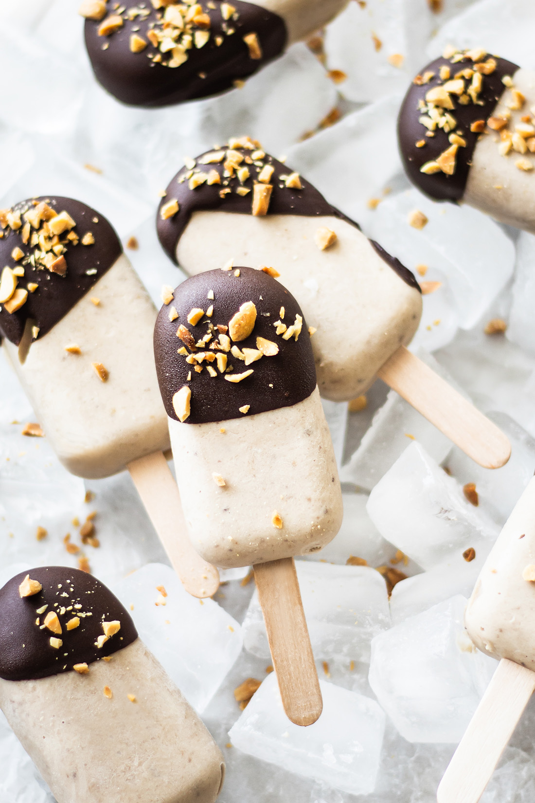 Peanut butter banana popsicles decorated with chocolate glaze and chopped peanuts
