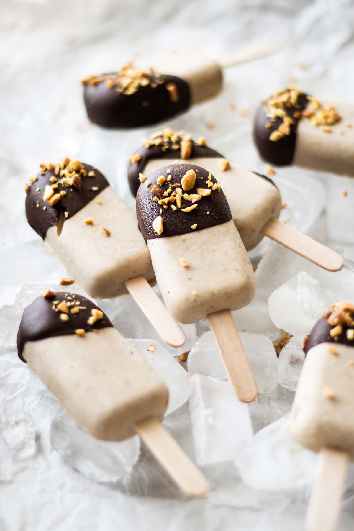 Ice cream bars on sticks, decorated with peanuts and chocolate
