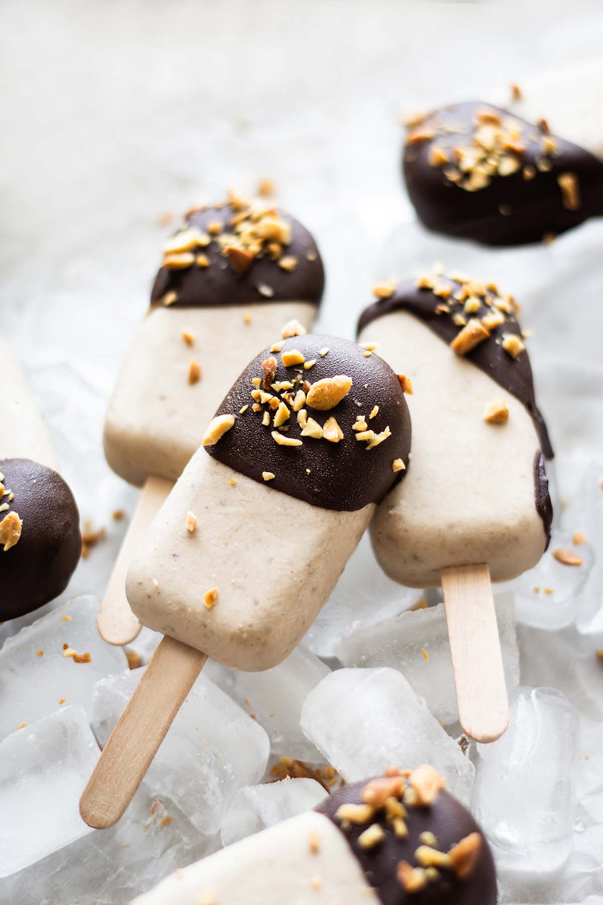 Peanut Butter Banana Popsicles laying on ice