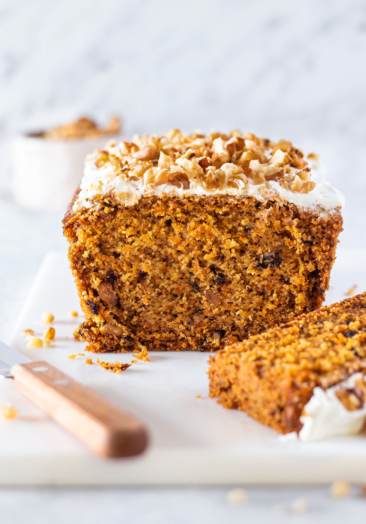 Gluten-free Carrot Cake Loaf, topped with frosting and chopped walnuts