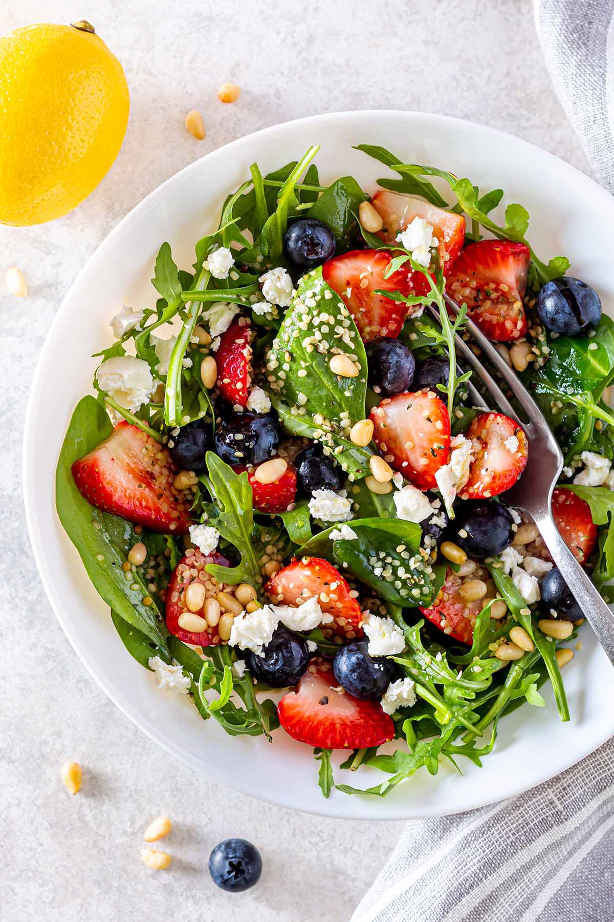 Green salad with strawberries, blueberries and feta chese in a serving plate