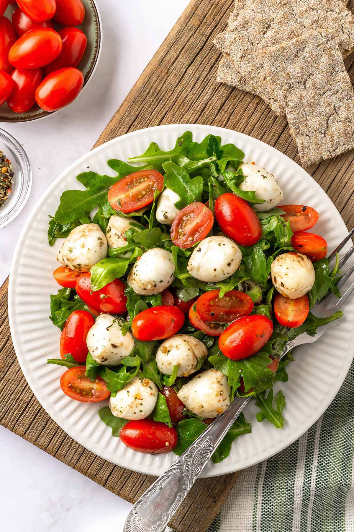Arugula Mozarella Salad with Tomatoes on a white serving plate