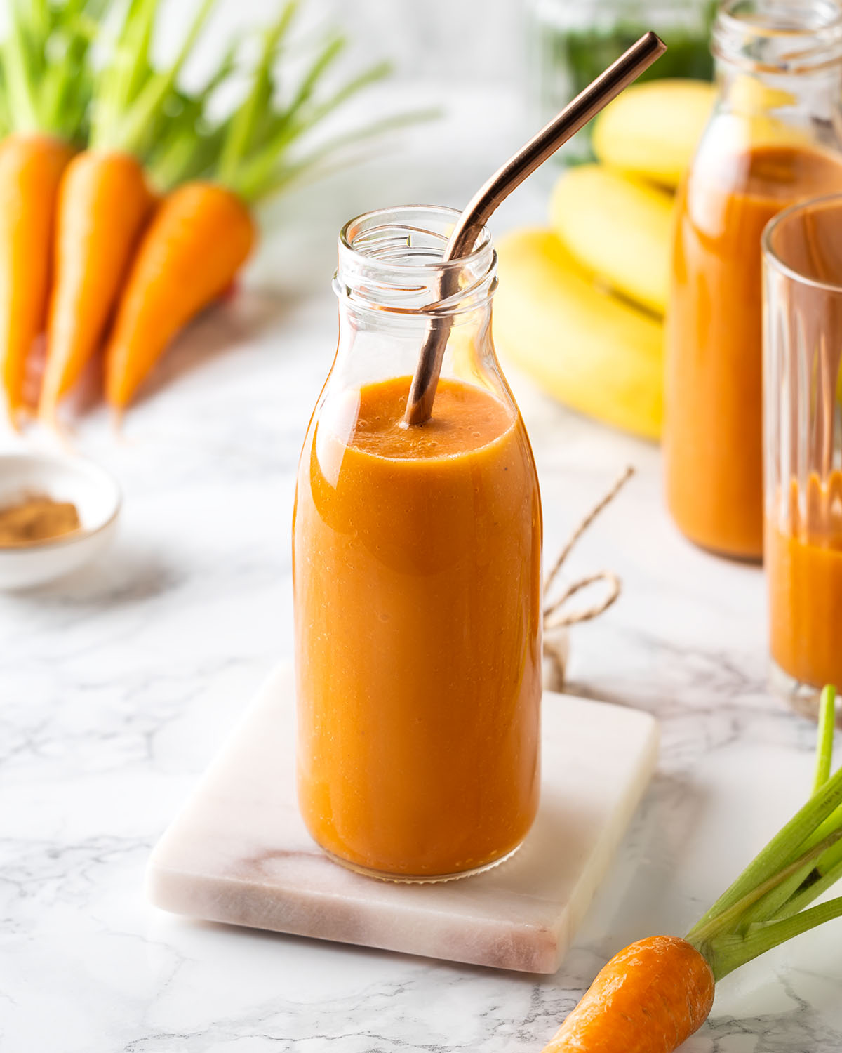 Carrot banana smoothie in a bottle with a straw inside