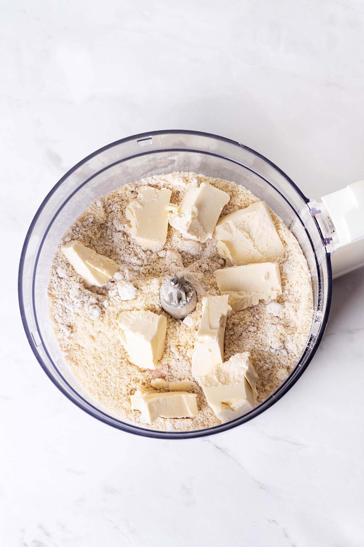 Dry ingredients for pie crust and a butter in food processor