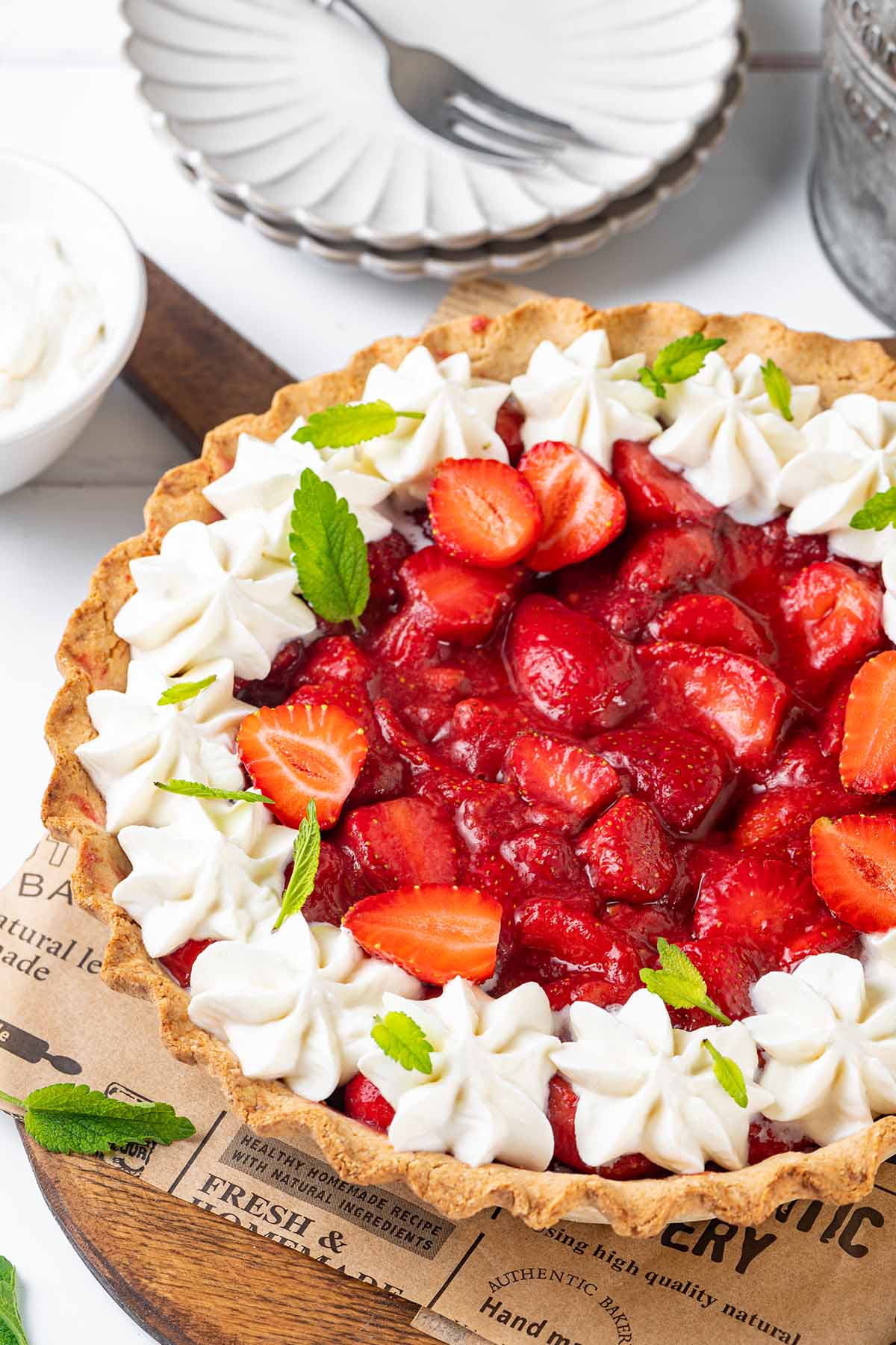 Gluten-free strawberry pie decorated with coconut whipped cream and leaves of mint on a serving board