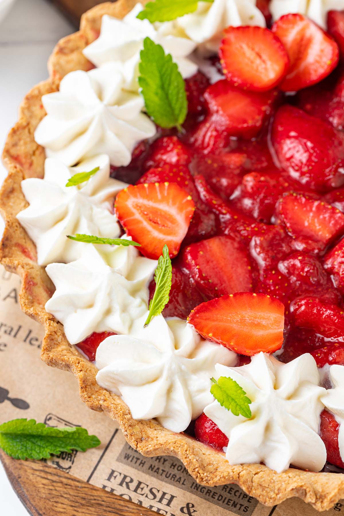 Strawberry pie decorated with coconut whipped cream and leaves of mint