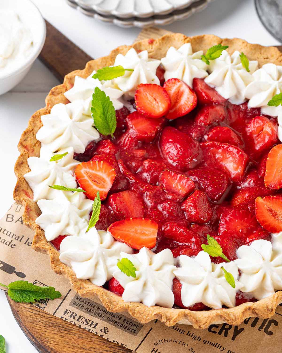 Gluten-free strawberry pie decorated with whipped coconut cream and leaves of mint