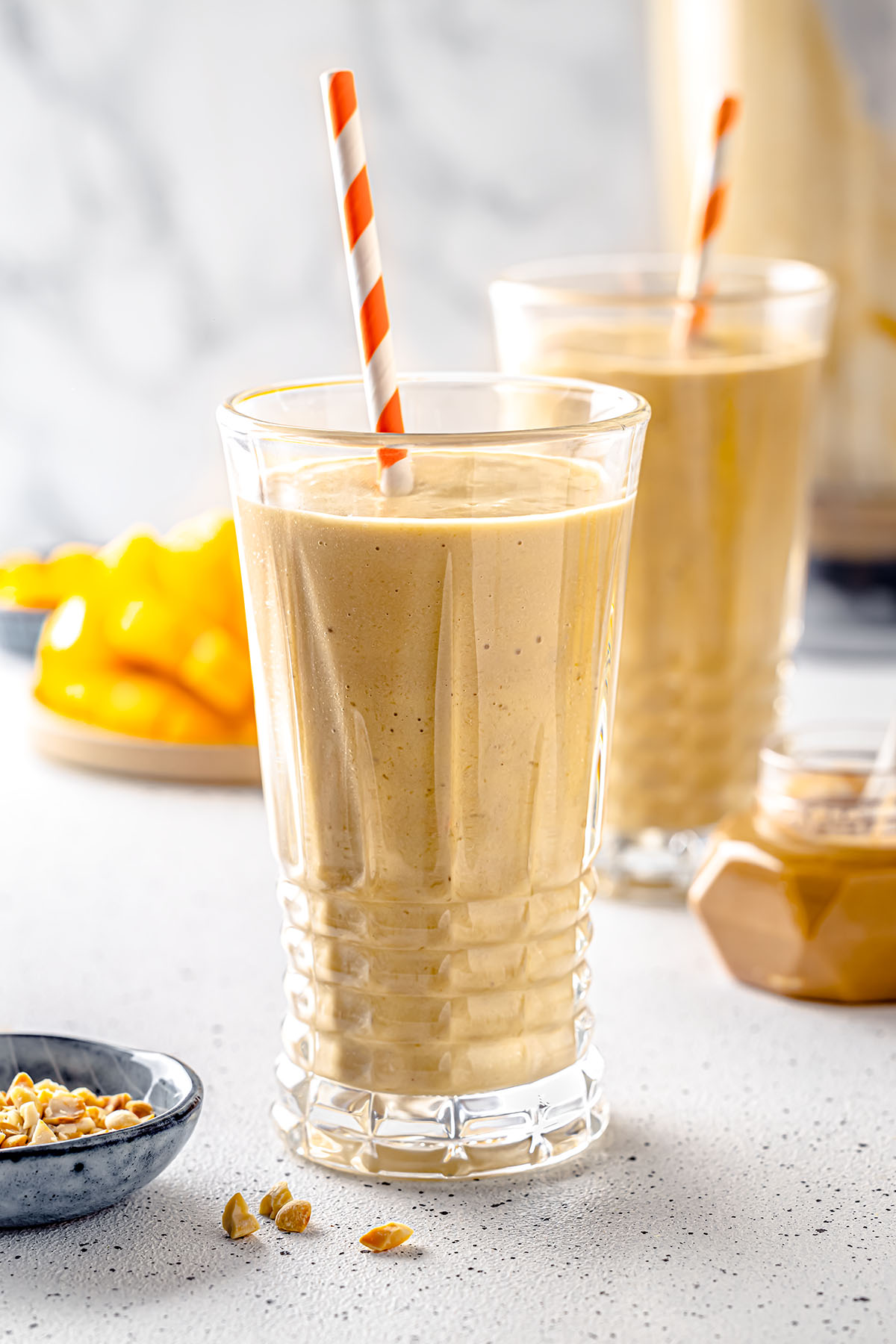 Mango peanut butter smoothie in glasses with straws