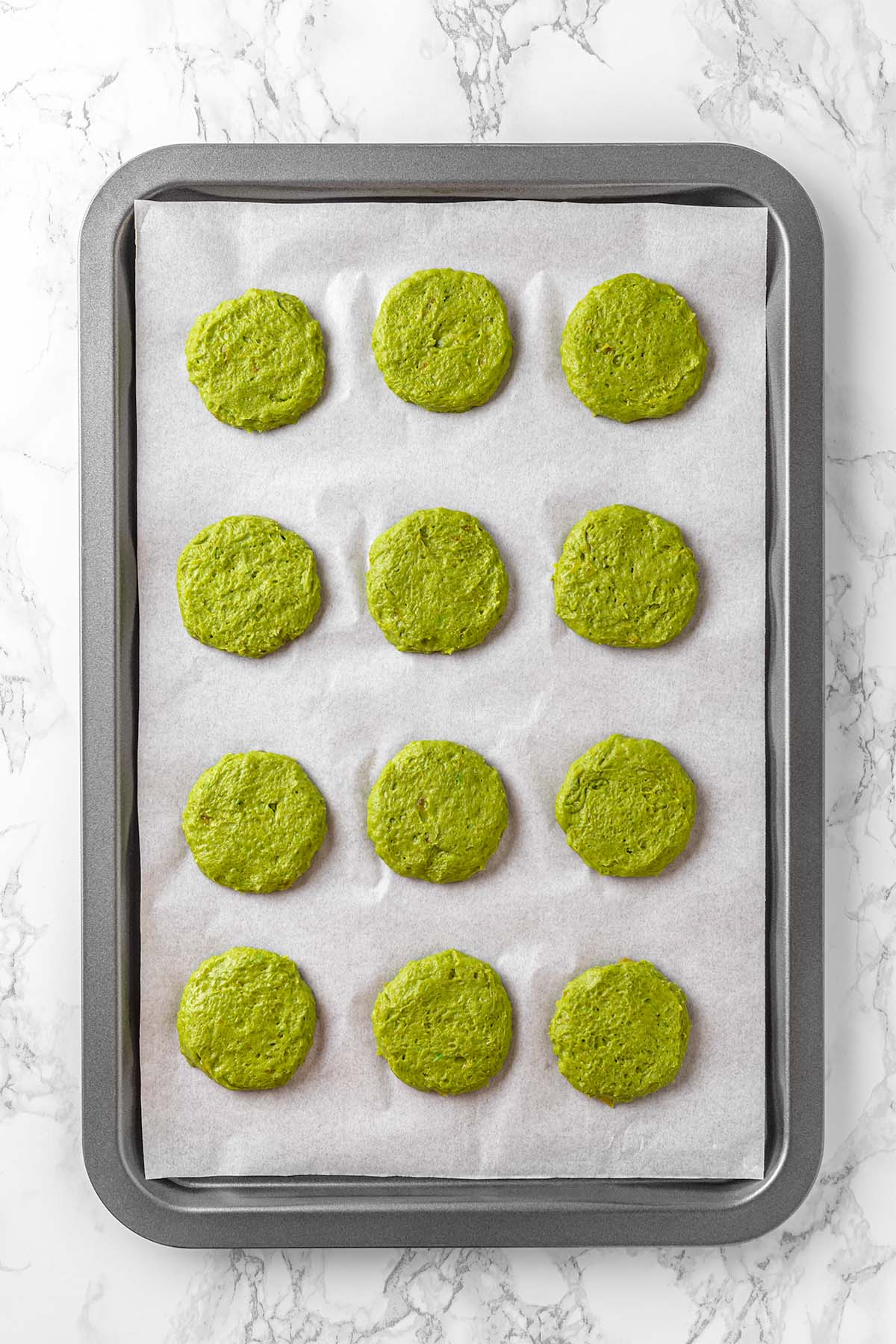 Green cookies on a baking sheet before baking