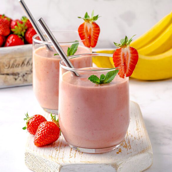 Two glasses with strawberry banana avocado smoothie decorated with mint and strawberry