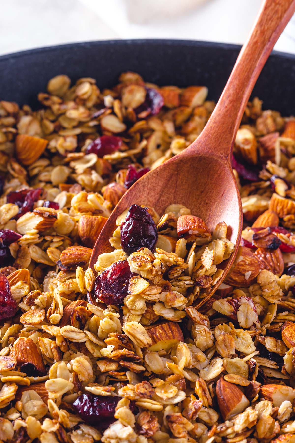 Granola with almonds and cranberries with a wooden spoon