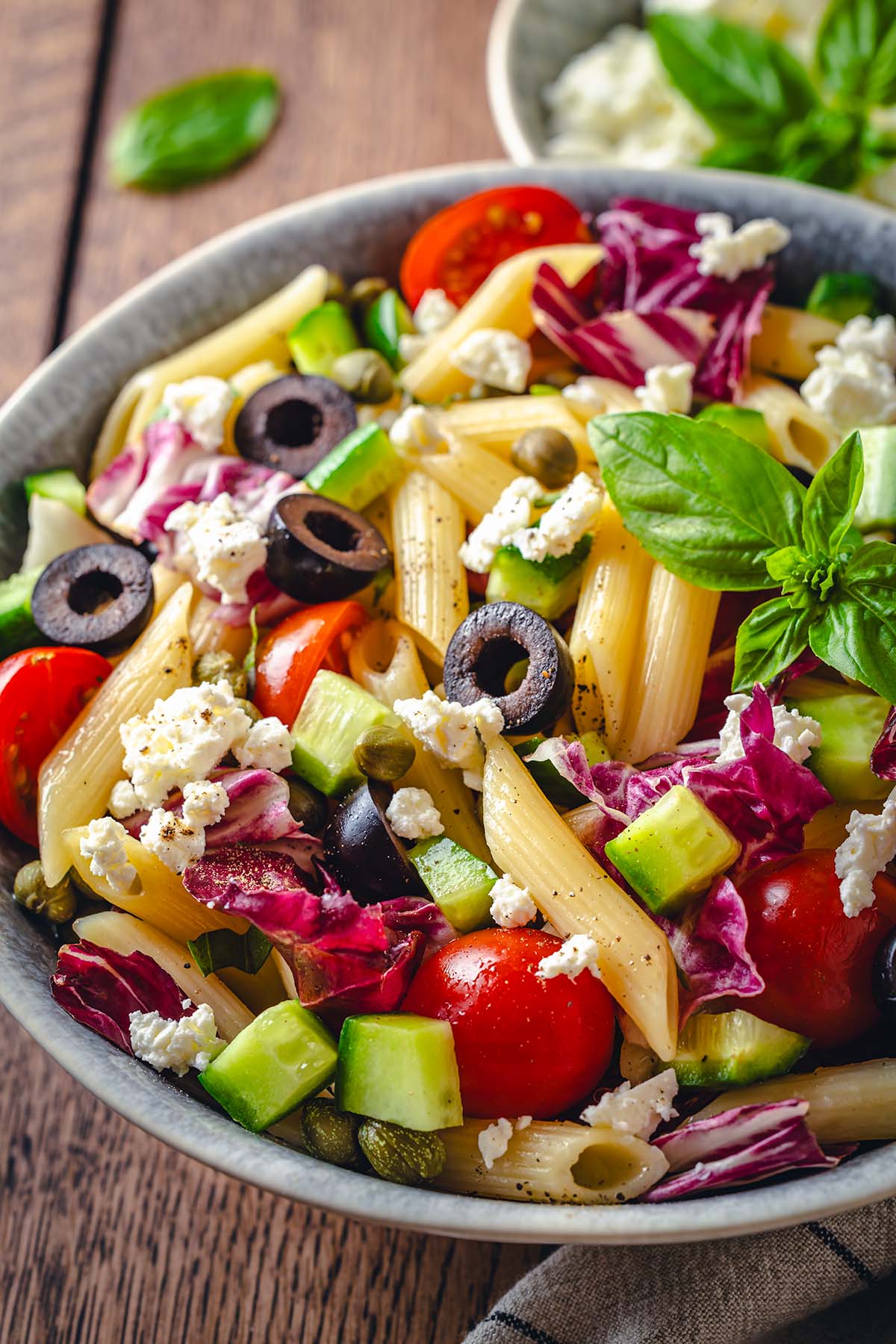 Sicilian salad with penne pasta, basil and ricotta in a serving bowl
