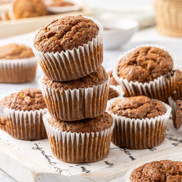 Stack of three Banana Poppy Seed Muffins on a wooden white board